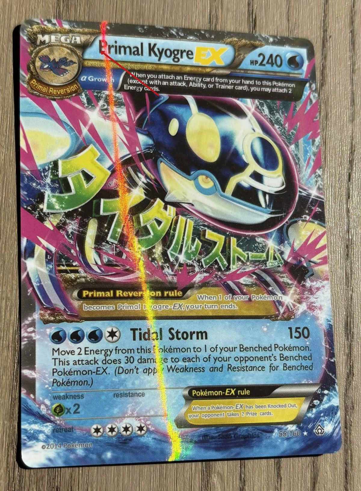 Counterfeit Primal Kyogre EX tilted under window light: the same thin rainbow line, marked with an arrow.