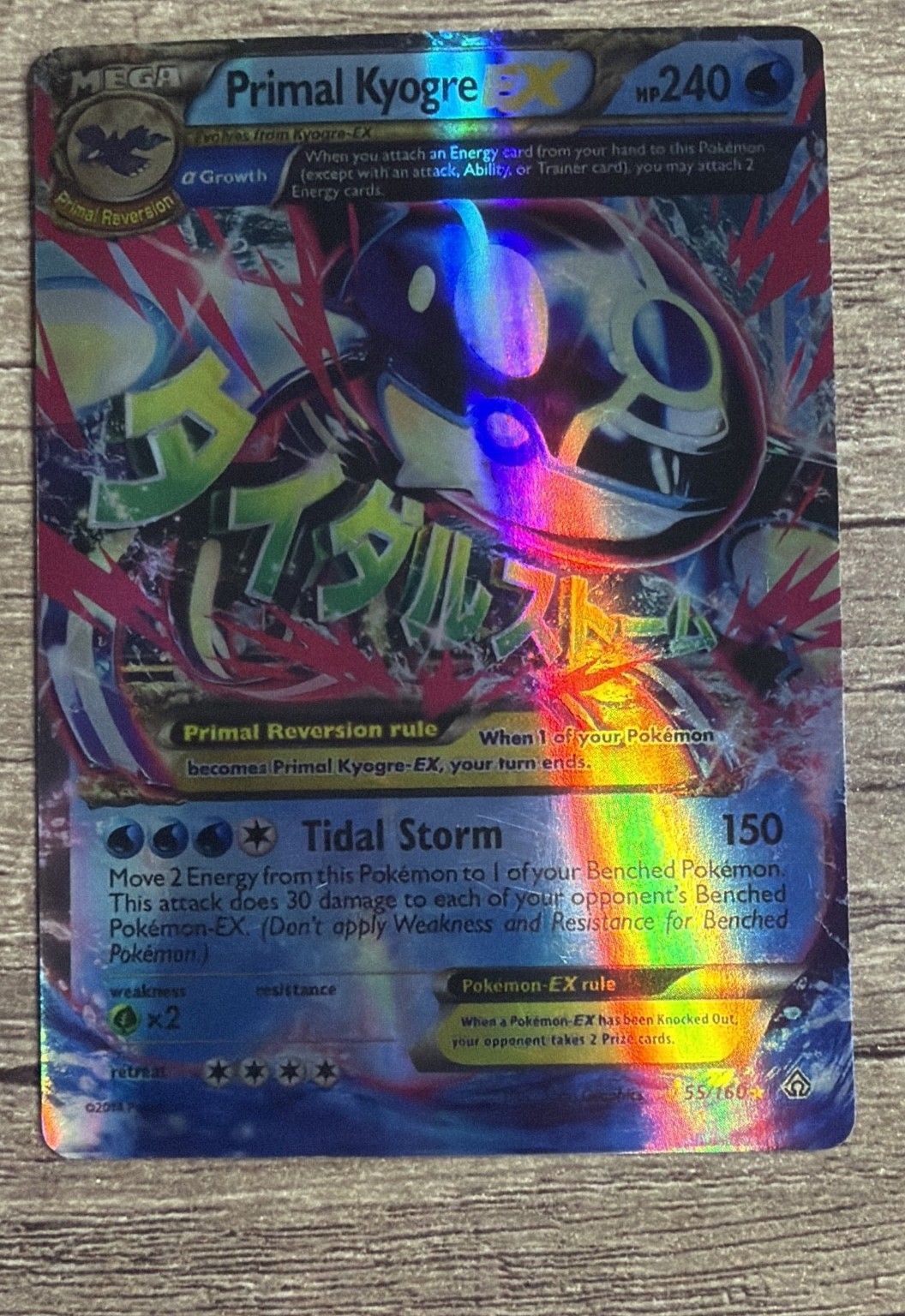 A genuine Primal Kyogre EX under a lamp: the same broad rainbow sweep, bending with the art and the text boxes.