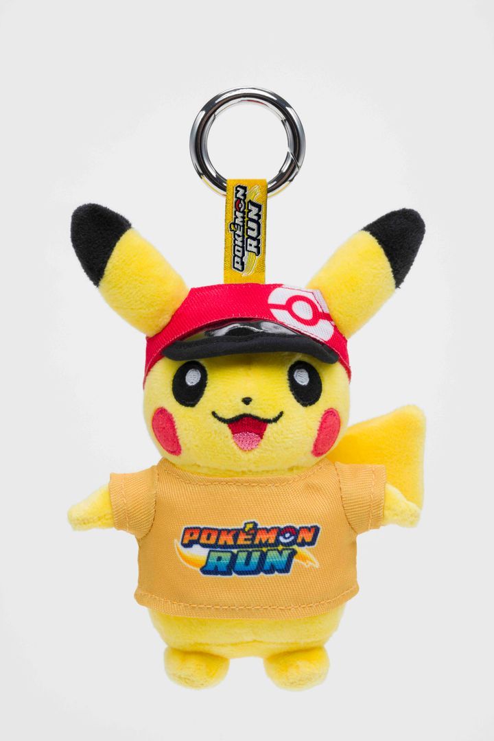 A small Pikachu plush charm in a red cap and an orange Pokémon RUN T-shirt, on a silver ring with a Pokémon RUN tag.
