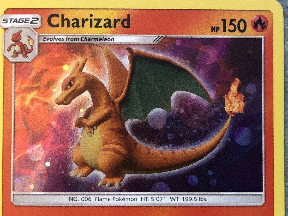 Macro photograph of a Sun & Moon era promo Charizard artwork window: finer, rounder orbs and thin swirls.