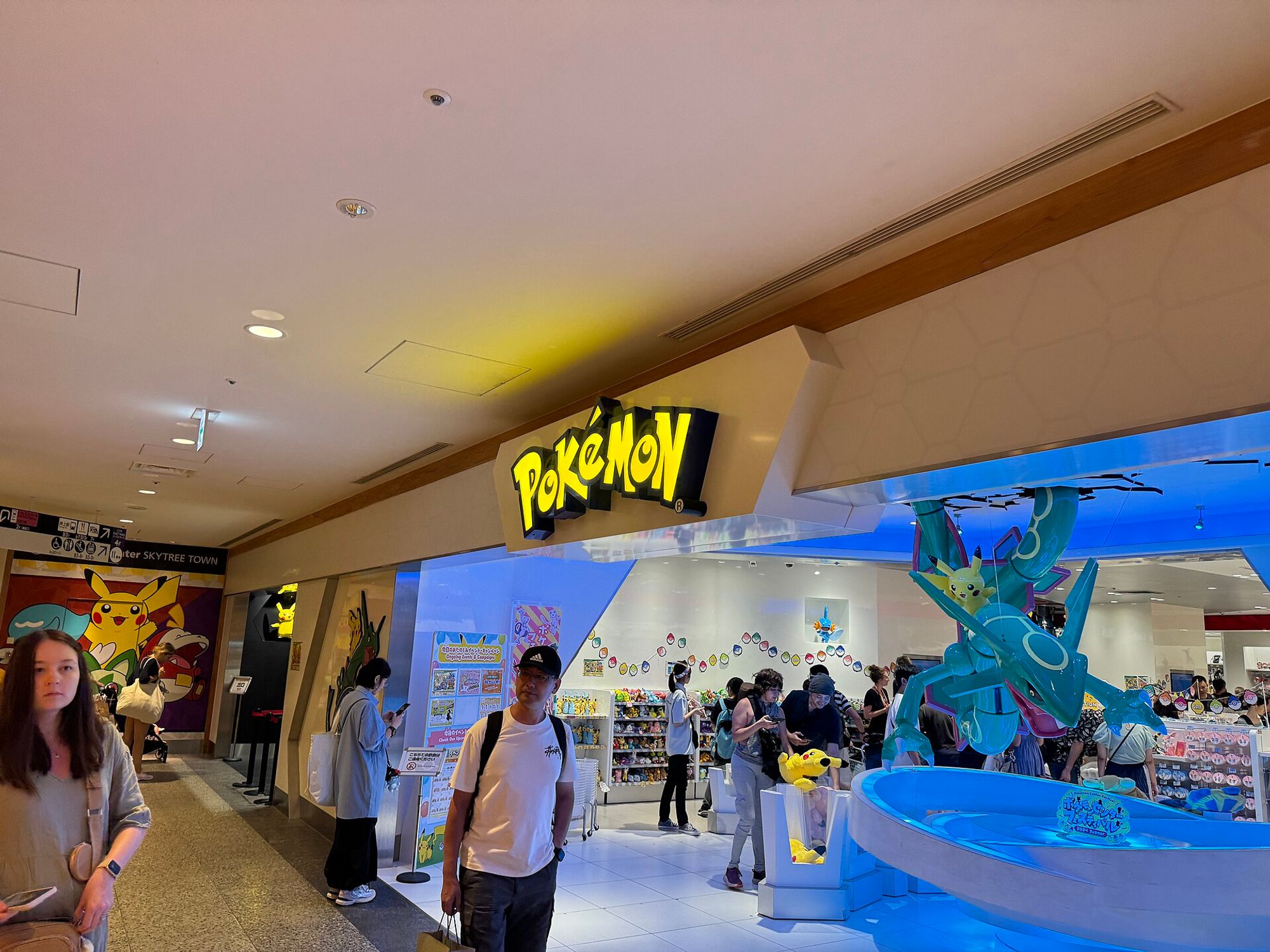 A life-size Rayquaza rising from a lit basin at the entrance of Pokémon Center Skytree Town, with a Pikachu perched on its coils.