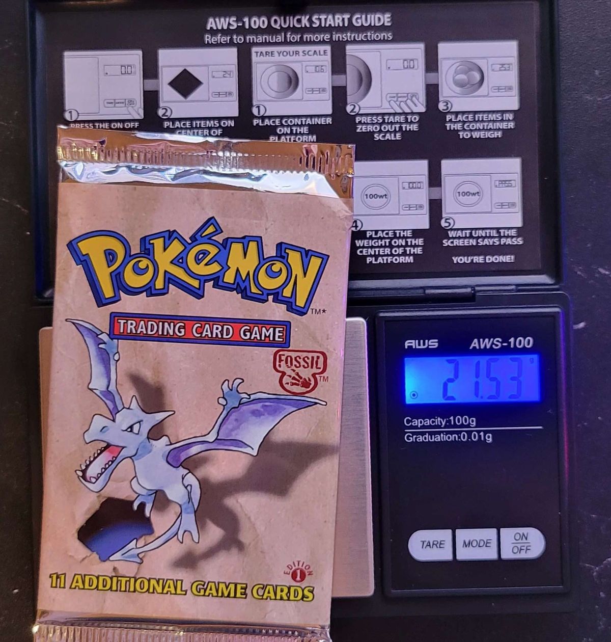 A Fossil 1st Edition pack on a 0.01 g scale reading 21.53 g.