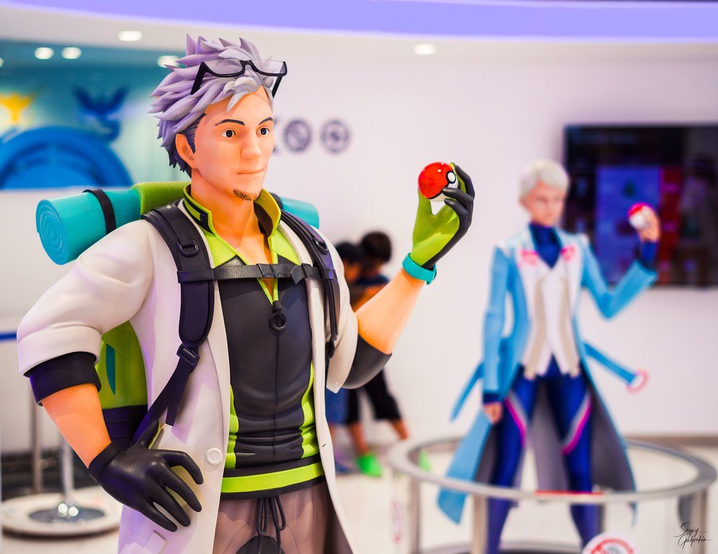 Life-size figures of Professor Willow and Blanche at Pokémon GO Lab., each holding a Poké Ball.