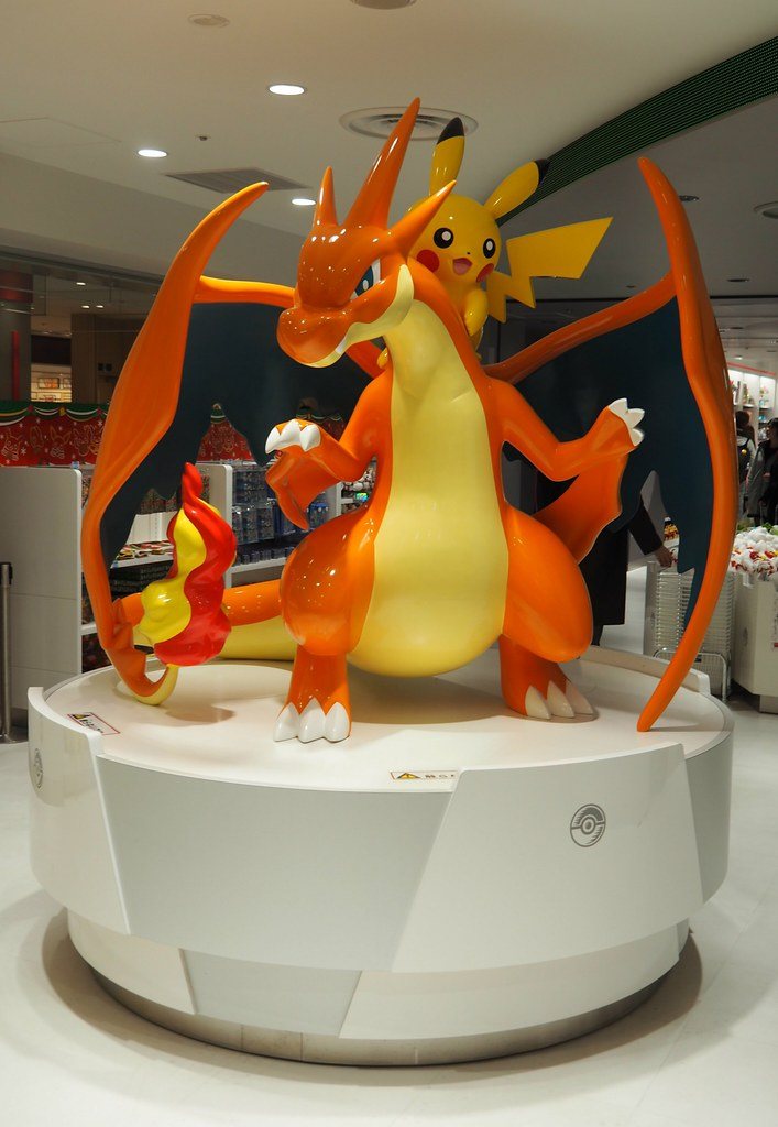 Life-size Mega Charizard X and Mega Charizard Y statues on a white plinth at Pokémon Center MEGA TOKYO.